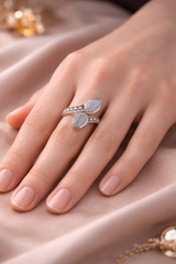 Bague Onde Cristalline – Aigue-Mmarine et Argent 925 autour d'un doigt, avec pierres cabochon bleutées et détails pavés scintillants.