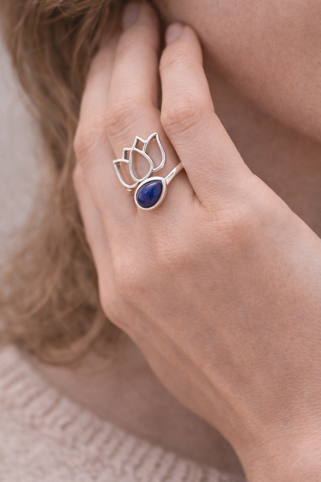Bague lotus argent 925 avec pierre lapis-lazuli, portée sur le doigt près de l’oreille, style délicat et élégant.