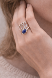 Bague lotus argent 925 avec pierre lapis-lazuli, portée sur le doigt près de l’oreille, style délicat et élégant.