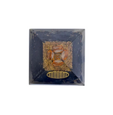 Orgonite Bouclier Sacré Tourmaline Noire – Fleur de Vie, pierre centrale orange dans un cadre noir avec motif doré et grille au fond.