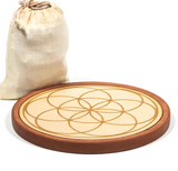 Grille de Cristal “Prospérité Dorée” posée à côté d’un petit sac en tissu, motif circulaire géométrique doré sur bois.