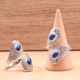 Bague voilée en argent 925 avec lapis-lazuli bleu et motif texturé, présentée sur un support conique et à côté.