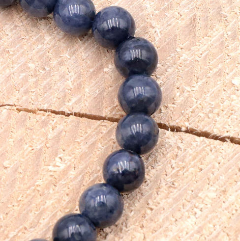 Bracelet Aura Royale en Saphir Bleu – AA, gros plans de perles bleues en saphir sur bois, texture naturelle.