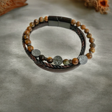 Bracelet en oeil de tigre et cuir avec motifs arbre de vie gravés sur des pendentifs gris, assemblé en double tour. Protection et force intérieure.