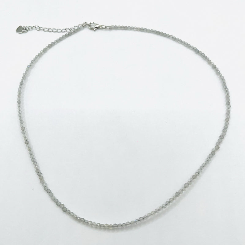 Collier Aura Mystique – Labradorite naturelle facettée: corde de petites pierres grises facettées, chaîne réglable avec fermoir et petit chaînette d’extension.