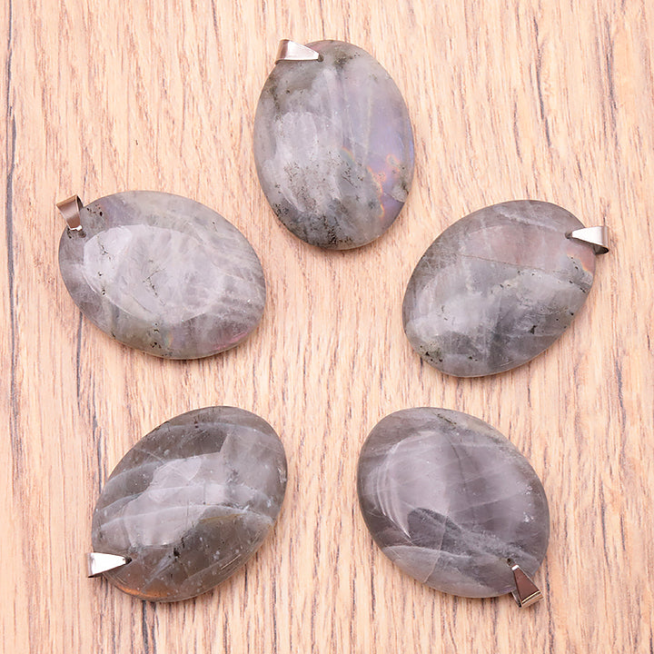 Pendentifs ovale en labradorite violette naturelle assortis, montés en attaches argentées sur bois clair.