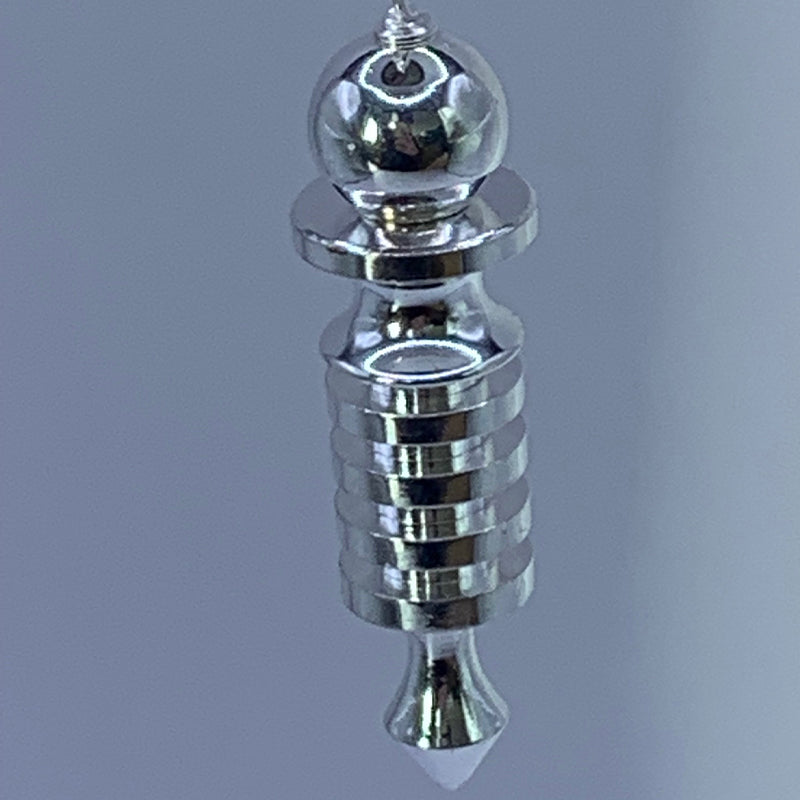 Pendule de Thot : détail d’une pièce argentée brilliante avec embout en pointe et sphère au sommet.