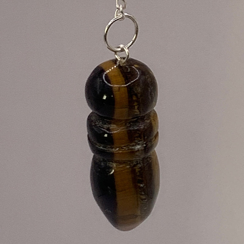 Pendule égyptien en œil de tigre avec chaîne et anneau argenté, forme cylindrique et lustrée.