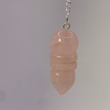 Pendule Egyptien en Quartz Rose en pendentif, chaîne et pièces nacrées visibles sur fond clair.